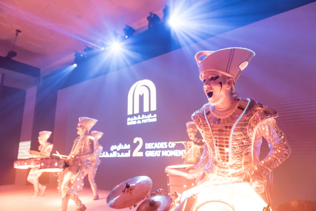 A Spark! performer roaring over a glowing drum, lit gold on a conference stage.