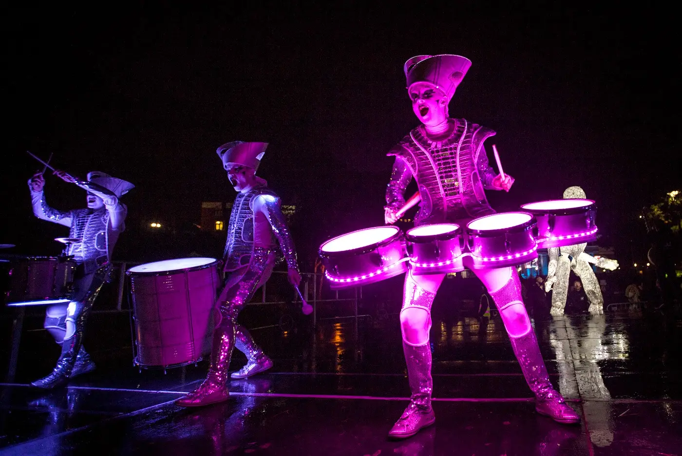 Spark! drummers on pink-lit drums with Dundu reaching down beside them in Bournemouth.