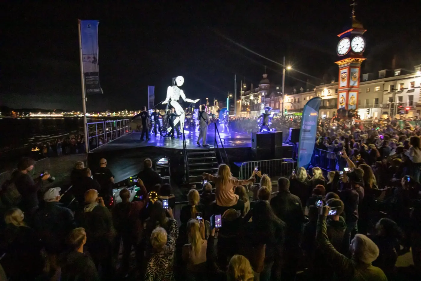 Dundu on the seafront stage in Weymouth beneath the Jubilee Clock Tower, a huge crowd watching.
