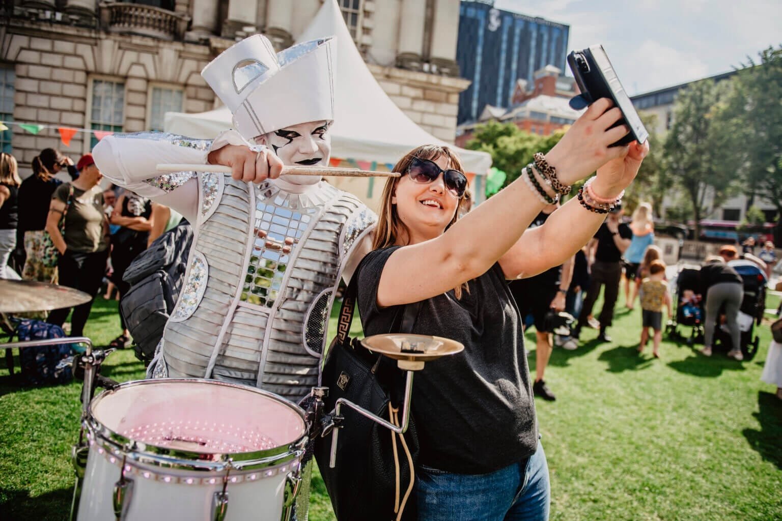A festival-goer taking a selfie with a Spark! performer at a sunny outdoor event